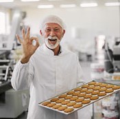 Old man baker holding pan with cookies