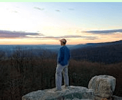 Man on rock outside watching sunset